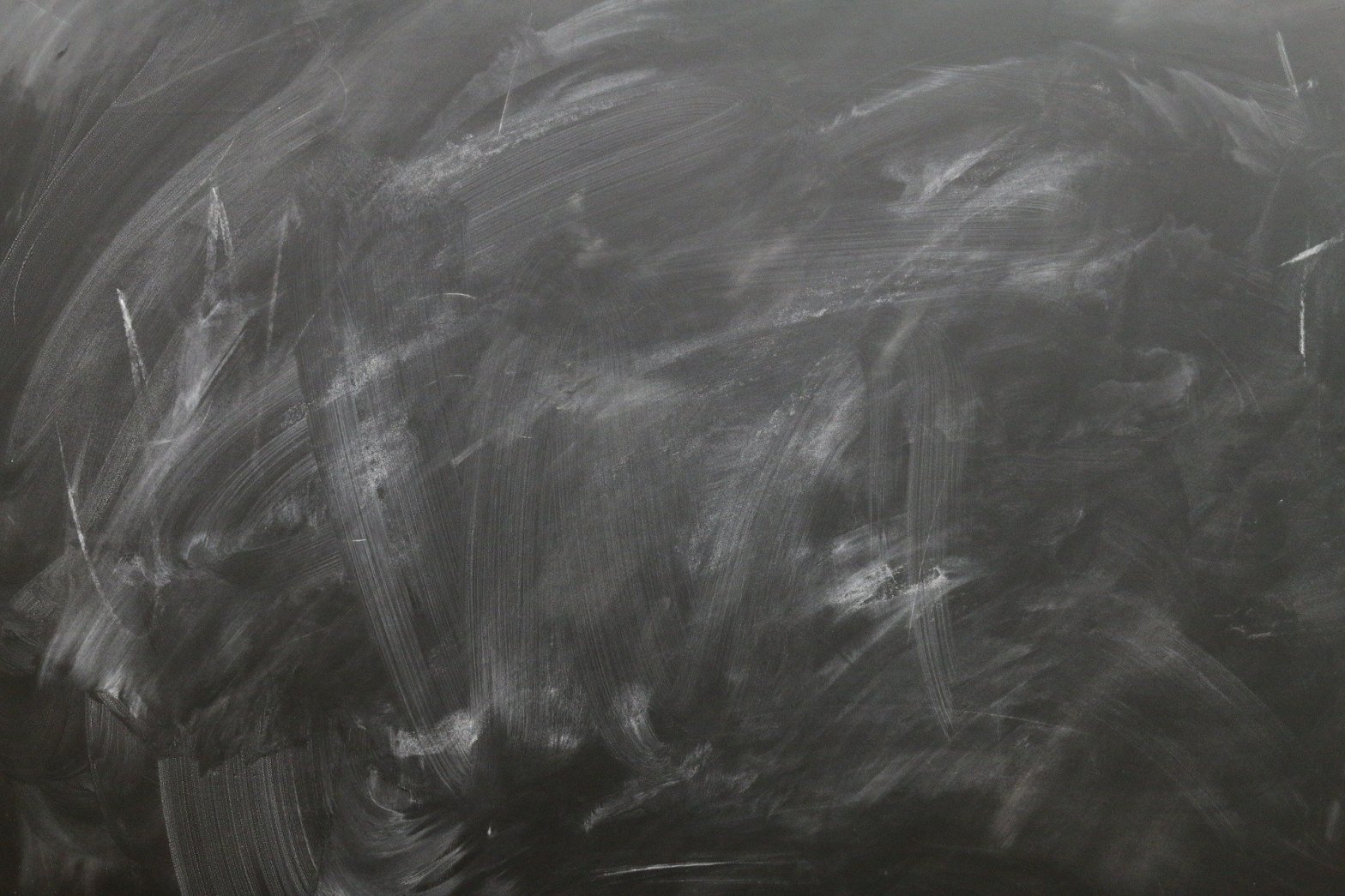 A blank blackboard with smeared chalk where the writing has been rubbed off